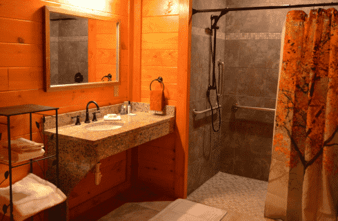 Spacious bathroom with granite vanity, large mirror, shelf with towels and large tiled shower