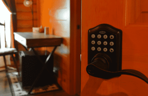 Black keypad door handle on a wooden door with writing desk in the background