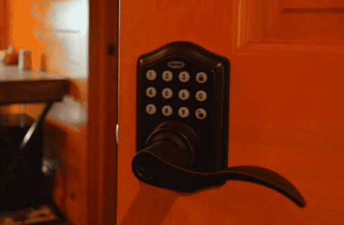 Black keypad door handle on a wooden door with writing desk in the background
