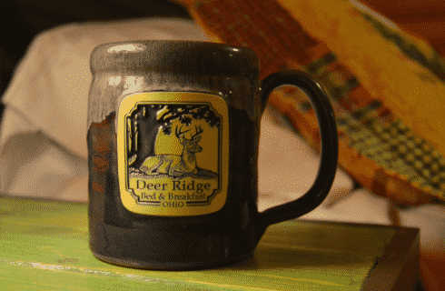 Blue ceramic mug with square business logo on a green bedside table