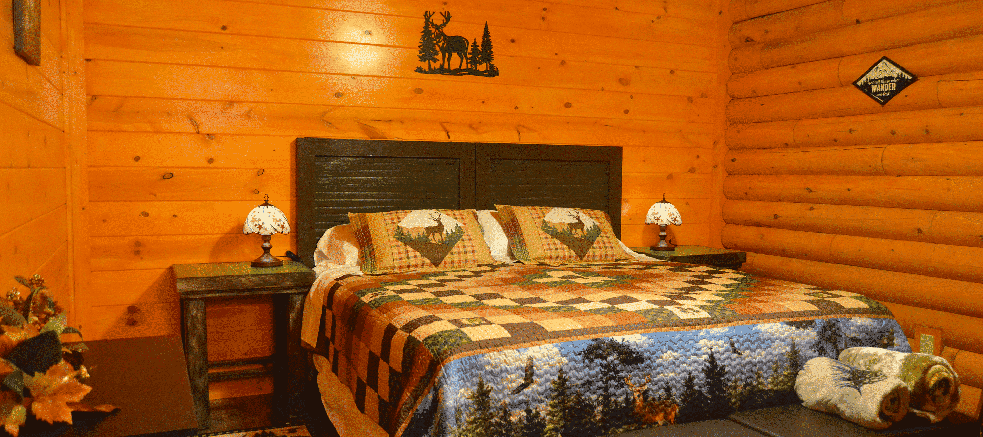 Quaint bedroom in a log home with king bed, colorful quilt and bedside tables with lamps