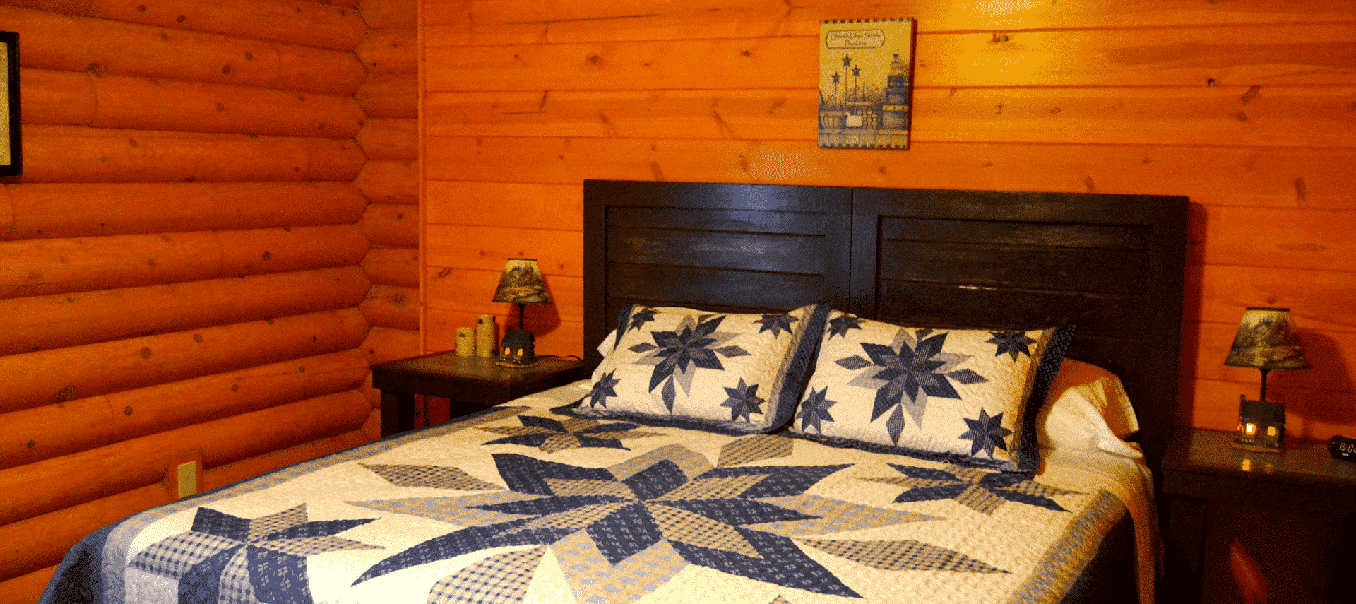 Bedroom in a log home with king bed, blue and white quilt and bedside tables with lamps