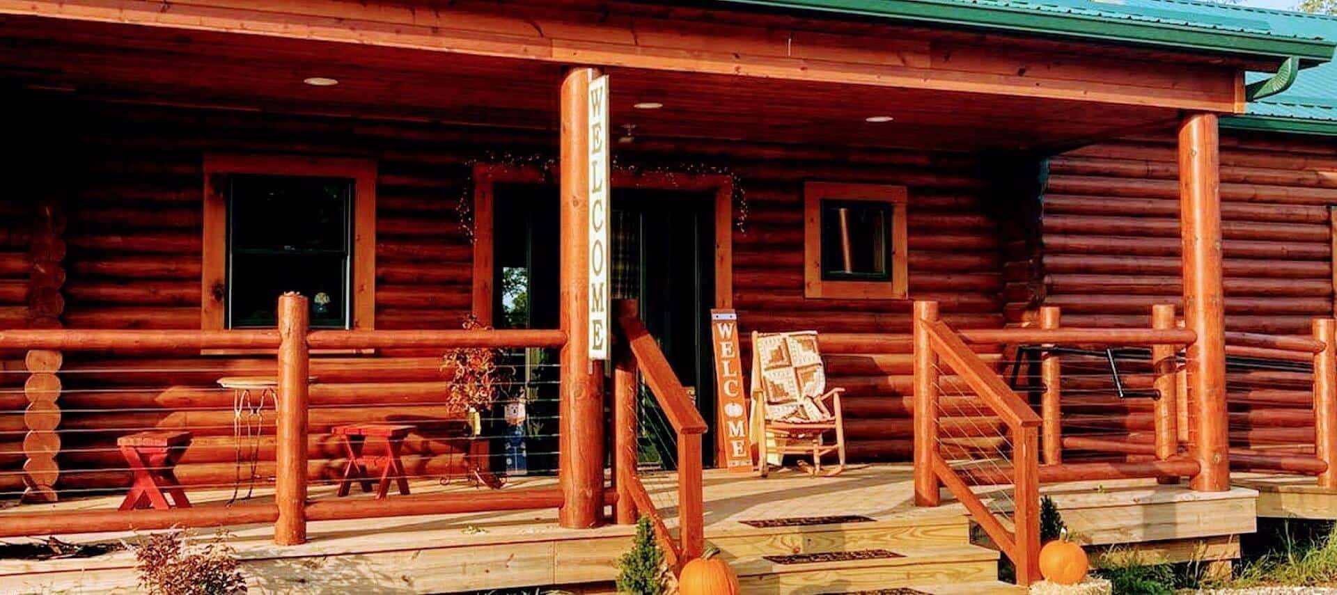 Front facade of a log home with a green roof and spacious front porch